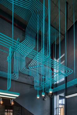 Bent piping, painted turquoise, continues throughout the space