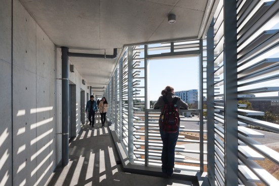 The dorm rooms are accessed via an open-air corridor behind the aluminum louvers on the southwest façade.