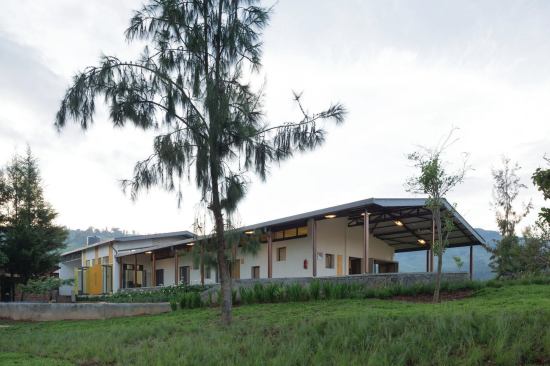 Surrounding the center are landscaped pathways lined by locally sourced volcanic stone, leading to the entrances and gardens for patients. 
