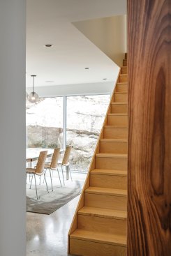 Large boulders visible from the dining room of Float, a residence in Halifax, shelter the house and inspired its fractured volume.