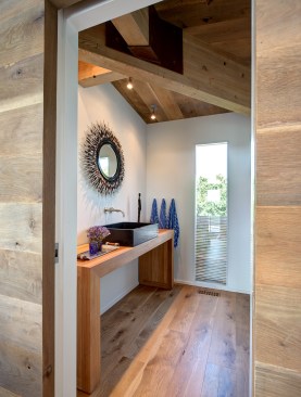 First-floor powder room: The bulk of the simple wood
vanity mirrors the hefty post-and-beam structure of the ceiling.