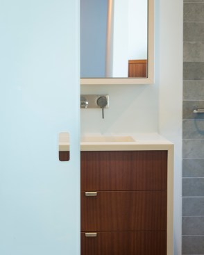 A view into the bathroom from the adjoining master bedroom shows the sleek sliding glass panel door separating the spaces.