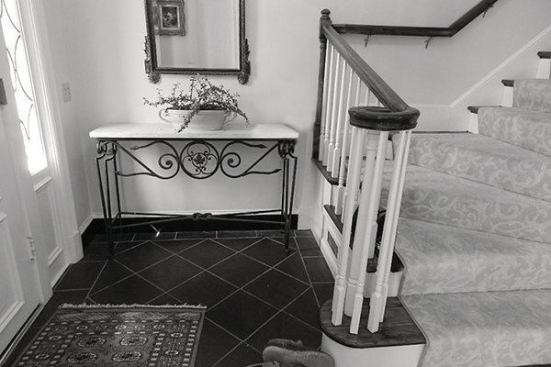 BEFORE: The existing main floor landing at the front entry way. The clients felt the wooden railing was dated and the turn blocked the pathway into the house.