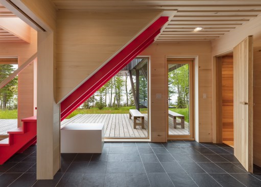 Red stair leading to second floor master suite with view to exterior dining area beyond.