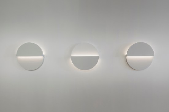A trio of the Cycladic Circle Small Sconces (above) shows two of the four orientations that the fixture can be mounted. The luminaire measures 14" by 14" by 2" and has a Corian Glacier White finish. The sconce is available in 2200K, 2500K, 2700K, 3500K with a CRI of 80 or 90 depending on color temperature selection. It uses 20W and provides 640 lumens. Color tuning is available on request.