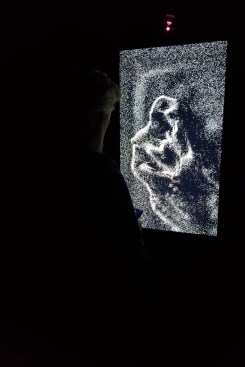 Artechouse's artistic director and co-founder Sandro Kereselidze looking down at his phone while Fuse's "Snowfall" installation captures his silhouette at the "Everything in Existence" exhibition.