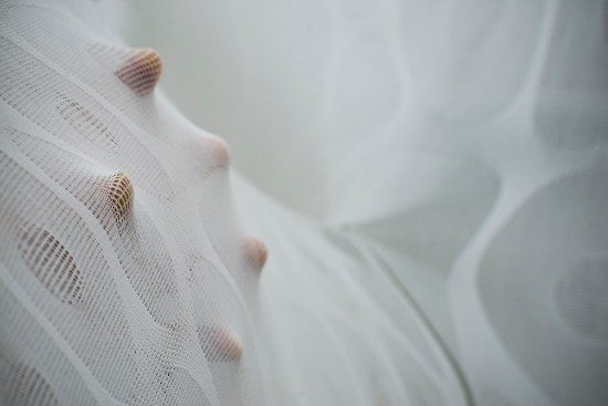 The CNC-knitted textile was developed through the design of elasticated yarn structures and variation of stitch patterns to produce a differentiated tactility across a range of scales to activate a broader sense of tactile engagement, from fingertip to sensory receptors in one's muscles and joints