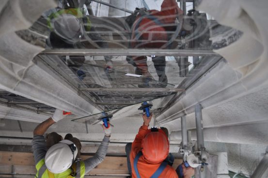Workers install protective glazing outboard of the stained glass.