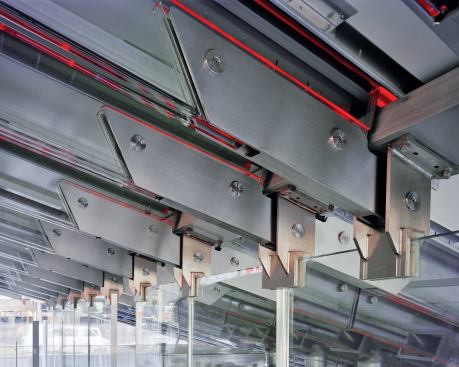 Glass stringer beams rely on the support of load-bearing glass walls to hold the weight of the booth's glowing red staircase and the tourists lounging upon it. The glass pieces are connected with stainless steel brackets and pins, but there is no load-bearing metal in the structure.