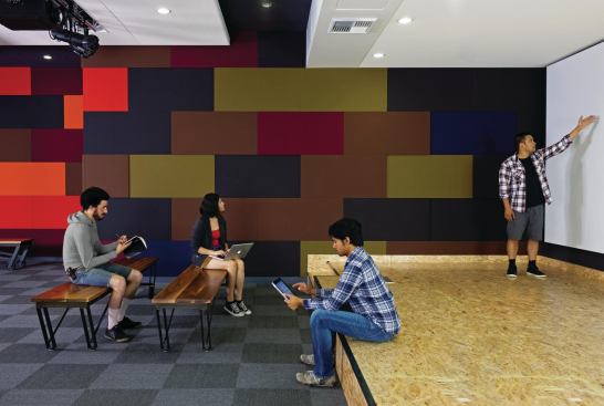 The ground-floor office suites are oriented around common resources, such as this multipurpose presentation room. Here, colorful acoustic panels in different thicknesses line one wall to absorb sound while still adding texture to the space.