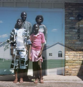 Laura Migliorino

Egret Street, 2006

Migliorino, a Minneapolis based artist, confounds the stereotype of suburbanites as white families with a mom, dad, and 2.5 kids. Her portraits of subdivision residents position people of all sorts in front of their own homes and against a superimposed backdrop of the larger neighborhood.