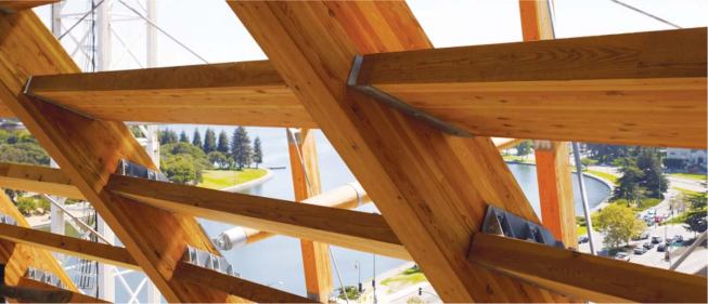 Glass is installed in a framework of vertical wooden members that form the canted and curving exterior wall. These wooden posts are secured to the interior wooden frame by a series of very thin steel cables and supports.