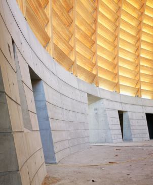 The interior space is defined by a curving, arcing wall of fixed wooden louvers, which give off a warm glow when illuminated by the sun.
