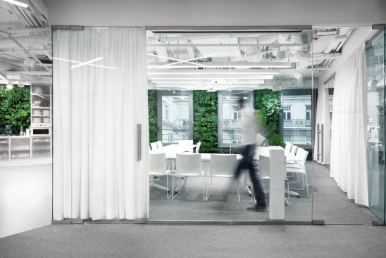 The conference room, which is one of the few enclosed spaces in the floor plan, features glass walls that can be closed off by opaque curtains.