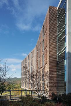 Split by a central service core, the six-story building has two canted wings. On the east fa&ccedil;ade these volumes are carefully placed to minimize views of the existing brick buildings slightly to the north.