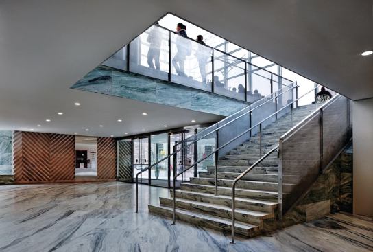 The stone-clad lobby features wall panels that mimic the diagonal etching on the façade panels.