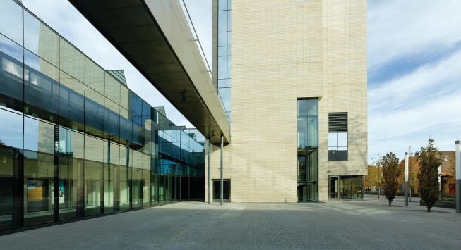 The eastern courtyard, with concrete pavers designed to mimic the shape of the building’s stone block, can be used for casual gatherings or performances. A bridge overhead connects a roof terrace atop the theater volume to the third floor of the arts tower. 