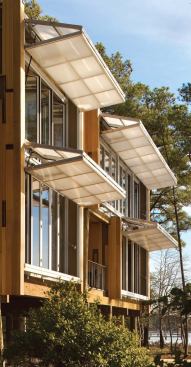 The outer layer on the façade of the Loblolly House is a bifold polycarbonate hangar door that doubles as a sunshade when locked in the open position. The translucent polycarbonate has many of the same thermal properties as glass, but it weighs less and keeps out the glare of direct sunlight.
