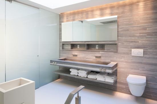 A wall tiled with Vals stone, quarried in Switzerland, rises through two floors of the apartment.