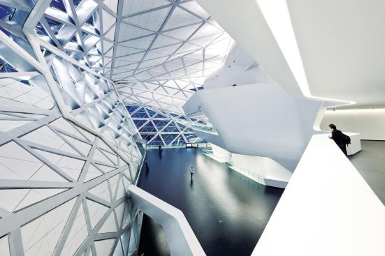 Balconies and staircases hang off the concrete structure of the main theater. Wall and ceiling panels set into the structural steel lattice follow the same triangular geometry as the granite panels do on the exterior. 