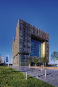 The headquarters building houses offices for more than 500 employees. A sunshading system controls glare and heat gain in the office spaces; the exposed glazing encloses a multistory atrium.