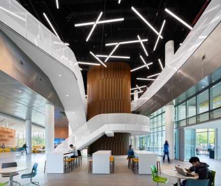Open stairs wrap around an elevator core clad in wood slats